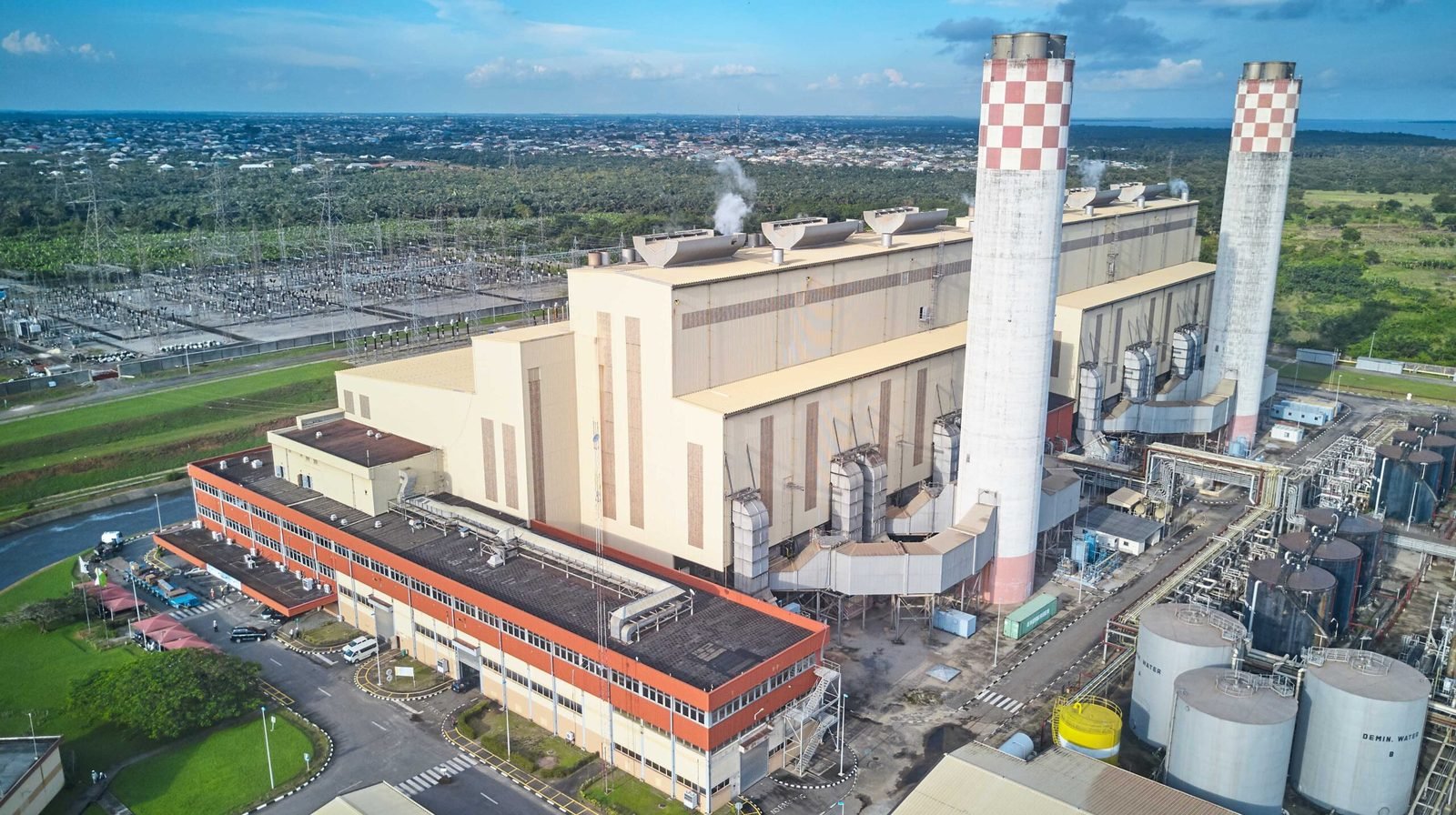 Aerial view of a power station with two tall red-and-white checkered chimneys